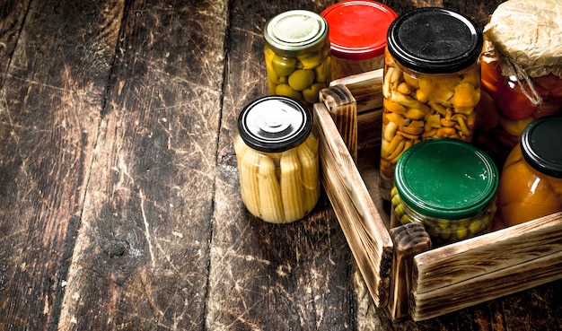Preserves mushrooms and vegetables in a box on wooden table.