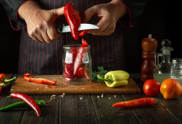 Preserving capsicum annuum in a spice jar The cook cuts red bell pepper in the kitchen Concept of preparing or canning vegetables