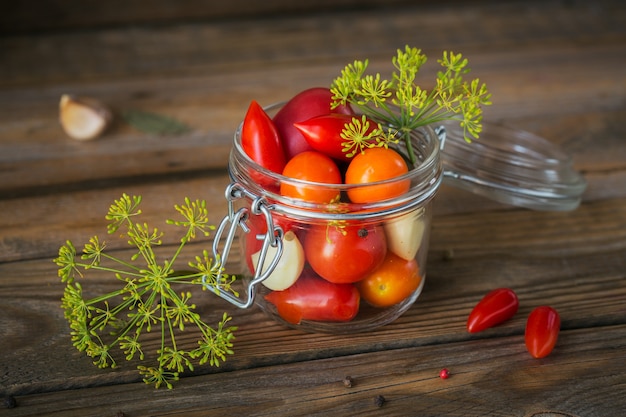 Preserving fresh and pickled tomatoes, seasonings and garlic on a wooden table. Healthy fermented food. Home canned vegetables.