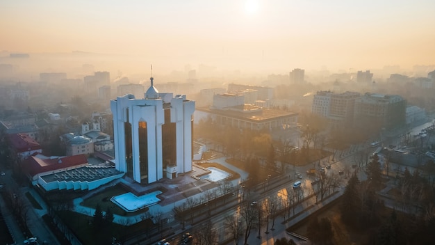 L'edificio della presidenza all'alba a chisinau, in moldova. nebbia nell'aria, alberi spogli, edifici, strade.