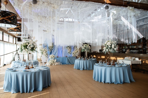The presidium of the newlyweds in the banquet hall of the restaurant is decorated with candles and green plants, wisteria hangs from the ceiling
