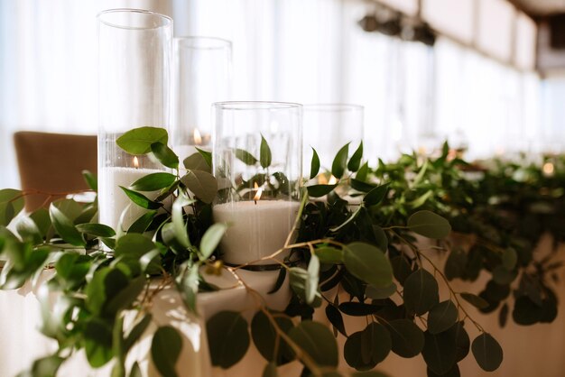 The presidium of the newlyweds in the banquet hall of the restaurant is decorated with candles and green plants wisteria hangs from the ceiling