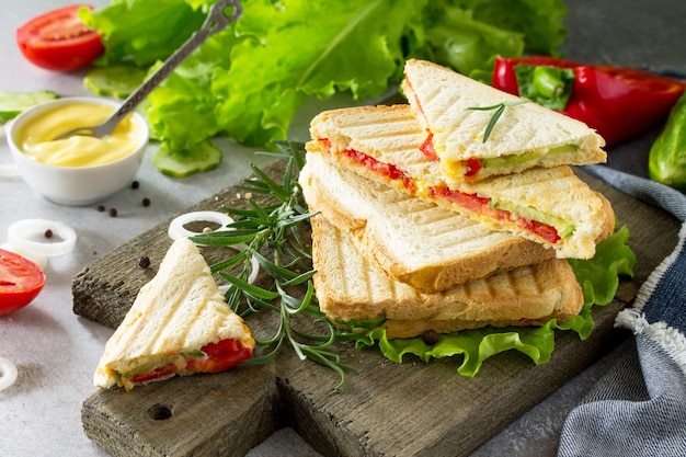 Фото Прессованный и поджаренный двойной сэндвич со свежими овощами и сыром на фоне серого камня
