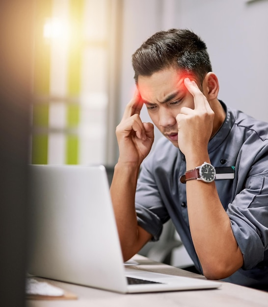 The pressure is getting to him Shot of a young man suffering with a headache while working on his laptop