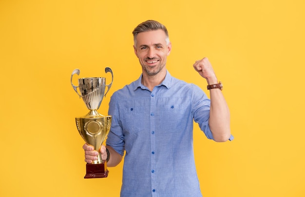 Prestatieprijs motivatie van zakelijk succes trofee en prestige kreeg prijs man viert overwinning inspiratie en motivatie gelukkige volwassen man houdt gouden beker vast