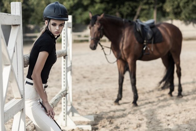 Prestige sportsman posing in hippodrome near hourse