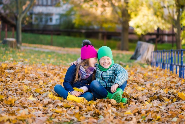 Preteen boy and girl play with yellow foliage