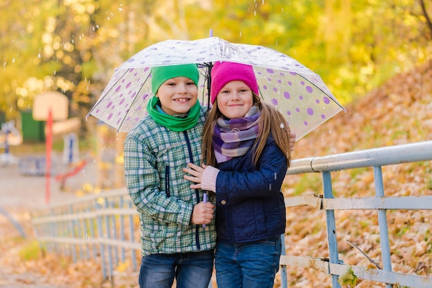 雨の公園を歩くプレティーンの男の子と女の子
