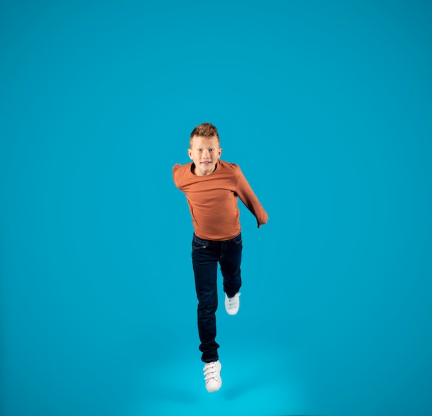 Preteen boy jumping in air and looking at camera