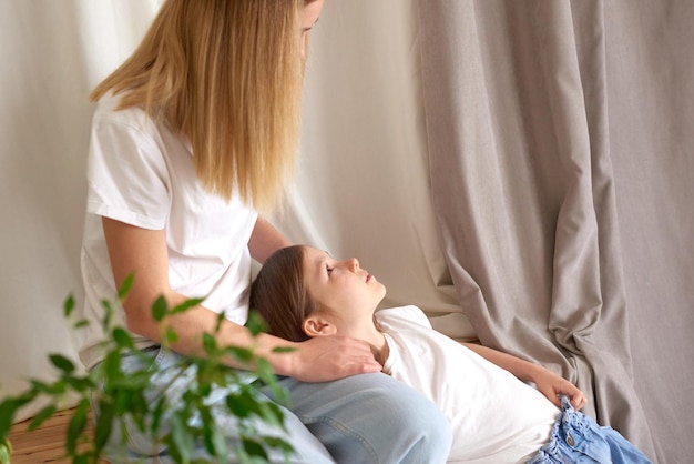 Preteen dochter ligt thuis op haar moeders schoot concept van zorgzame familierelaties vertrouwen