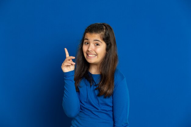 Preteen girl with blue jersey gesturing over blue wall