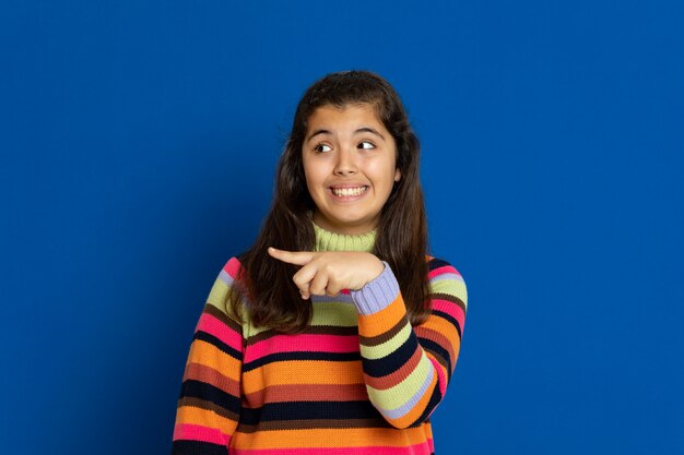 Preteen girl with striped jersey gesturing over blue wall