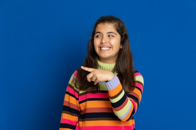 Preteen girl with striped jersey gesturing over blue wall