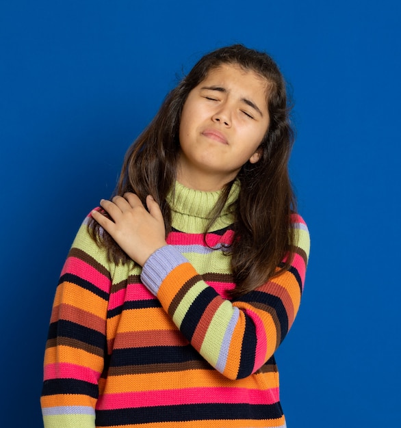 Preteen girl with striped jersey gesturing over blue wall