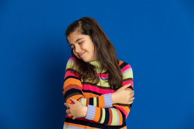 Preteen girl with striped jersey gesturing over blue wall