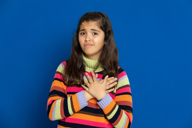 Preteen girl with striped jersey gesturing over blue wall