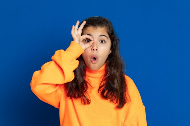 Preteen girl with yellow jersey gesturing over blue wall