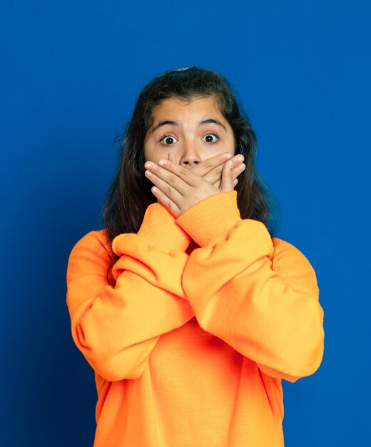 Preteen girl with yellow jersey gesturing over blue wall