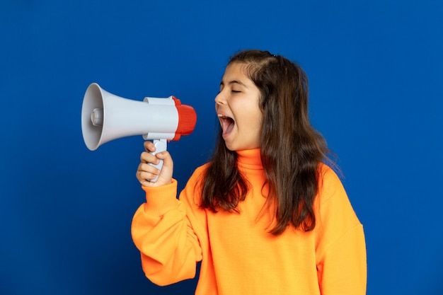 Ragazza del preteen con la maglia gialla che gesturing sopra la parete blu