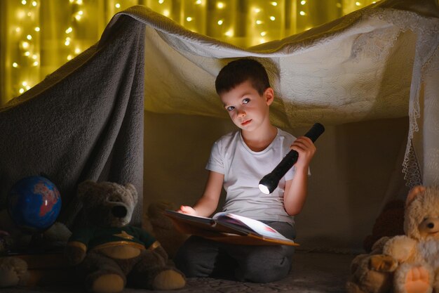 Preteen jongen met zaklamp leesboek thuis