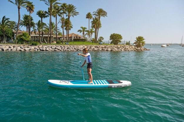 Photo preteen kid practicing stand up paddleboarding during summer vacation