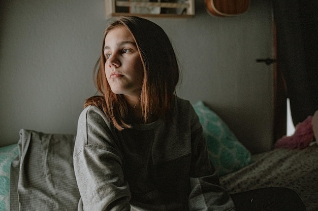 Foto pre-adolescente che guarda dalla finestra durante il blocco