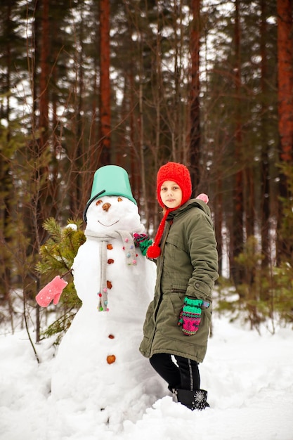 Foto preteen meisje in de winter om een sneeuwpop te beeldhouwen