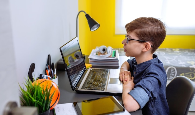 Preteen receiving class at home with laptop from his bedroom home schooling concept