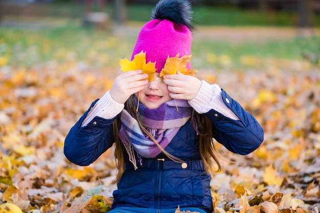 Preteen vrouwelijk kind spelen met gebladerte in herfst park