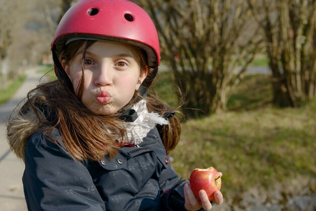 Preteen with roller skate helmet, eat an apple