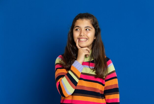 Preteenmeisje met gestreepte jersey die over blauwe muur gesturing