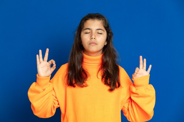 Preteenmeisje met het gele gesturing van Jersey over blauwe muur