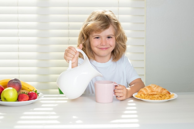 Pretten child pouring whole cows milk schoolkid eating breakfast before school portrait of child sit