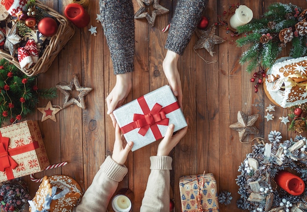 Prettige kerstdagen en fijne feestdagen Een man en vrouw met kerstcadeau Cadeaus en handen