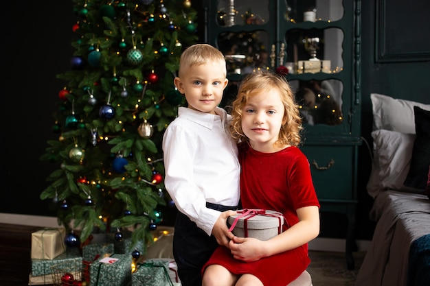 Prettige kerstdagen en fijne feestdagen Schattige kleine kinderen knuffelen in de buurt van de kerstboom en licht op de achtergrond