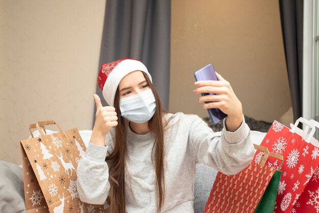 Prettige kerstdagen en gelukkig nieuwjaar meisje met een medisch masker feliciteert vrienden