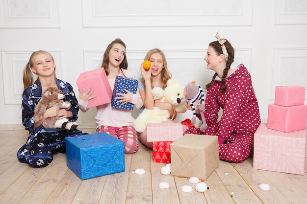 Prettige kerstdagen en gelukkig nieuwjaar Mooi gelukkig vier kind meisje in pyjama wachten op een wonder thuis met kerstboom. Klein lachend meisje met de doos van de gift van Kerstmis. Vakantie, mensenconcept.