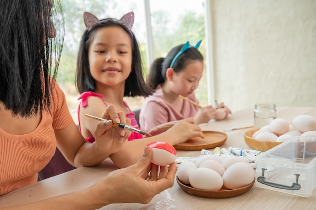 Prettige vakantie Moeder en haar twee dochters die eieren schilderen Gelukkige familie die zich voorbereiden op Pasen Aziatisch schattig klein kindmeisje met konijnenoren