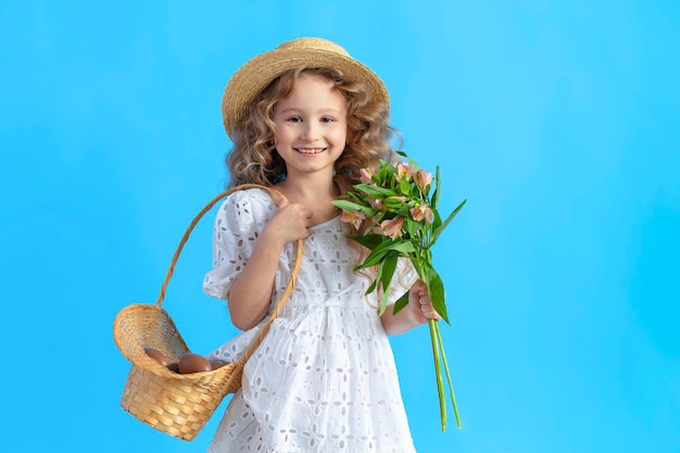 Prettige vakantie Pasen kinderen meisje met mand chocolade-eieren Lentebloemen op blauwe achtergrond