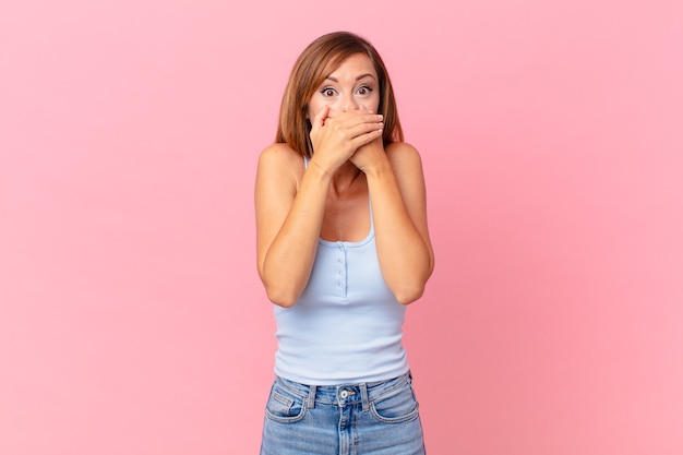 Pretty adult woman covering mouth with hands with a shocked