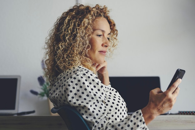 Pretty adult woman use mobile phone connection to call and work sitting at the office