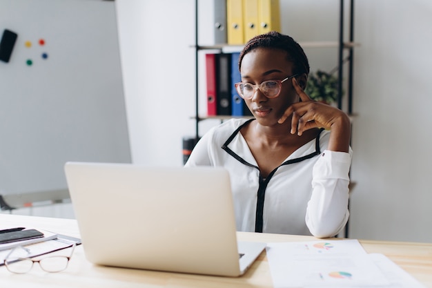 Pretty african american business woman working on laptop in office