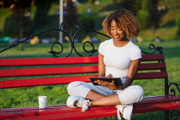 Pretty African American lady with a tablet in the park