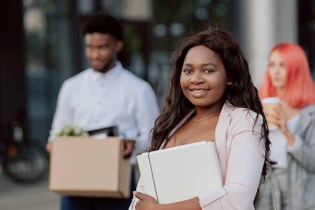 A pretty african american woman with walks out of the company office building with coworkers