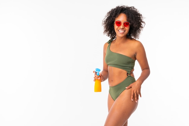 Pretty african female in swimsuit with spay can and smiles isolated