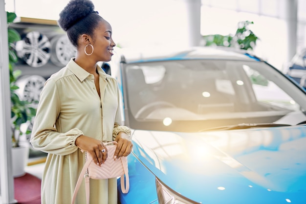 Pretty african lady liked automobile in cars showroom