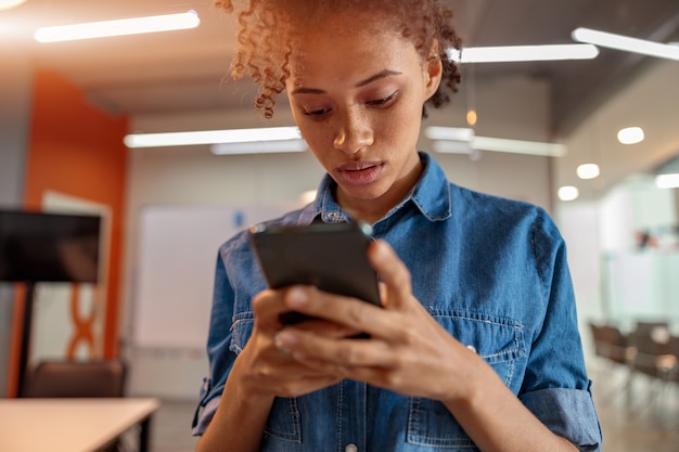 Foto bella donna afroamericana che usa il cellulare nella sala riunioni