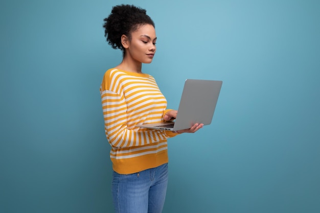 Giovane donna latina dell'ufficio del brunette abbastanza afro che tiene il computer portatile