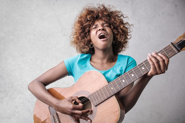 Pretty Afro girl playing on a guitar