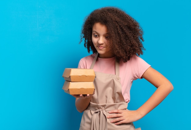 Pretty afro teenager girl chef with take away burgers boxes